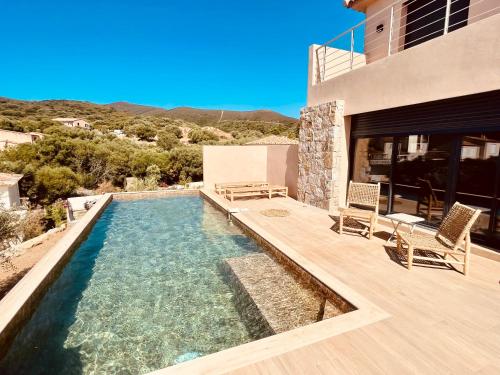 una piscina con due sedie e una casa di Villa Casa Maredda bord de mer avec piscine a Palasca