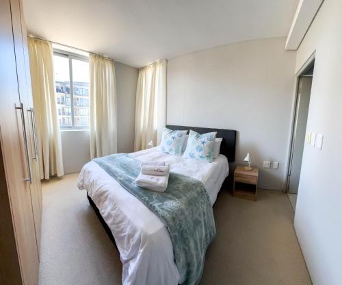 a bedroom with a large bed with blue pillows at Ilanga Africa Beach Front Apartments in Cape Town