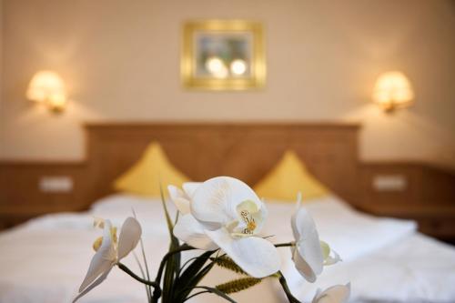 a vase of white flowers sitting on a bed at Dolomites Wellness Hotel Savoy in La Villa