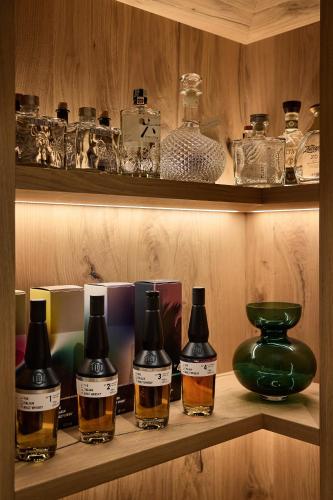 a shelf with bottles of whiskey and a vase on it at Dolomites Wellness Hotel Savoy in La Villa