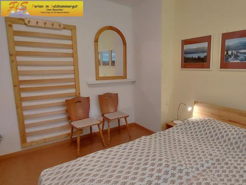 a bedroom with two chairs and a bed and a mirror at Apartment Urlaubstraum in Bad Mitterndorf
