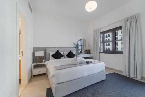 a white bedroom with a large bed and a window at Free housekeeping visits during your stay - StayShort - Restful 1-Bedroom Apartment at Al Andalus in Jumeirah Golf Estates in Dubai