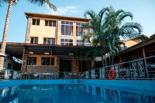 布琼布拉Pearl Residence Hotel的棕榈树建筑前的游泳池