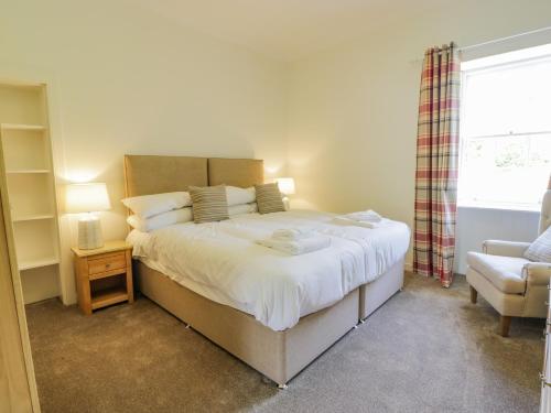 a bedroom with a large bed and a chair at North Firbank - Culzean Castle in Maybole