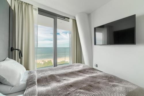 a bedroom with a bed and a view of the beach at Wave Front Sea View 7 Floor in Międzyzdroje