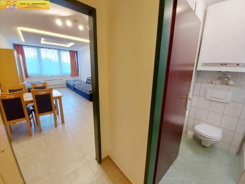 a bathroom with a toilet and a dining room at Apartment Christina in Tauplitz