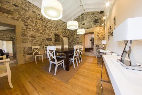 a dining room with a stone wall and a table and chairs at Casas de São Martinho in Arcos de Valdevez