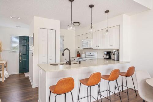 a kitchen with white cabinets and orange chairs at a counter at PCBV325 Anchor's Away in Manteo