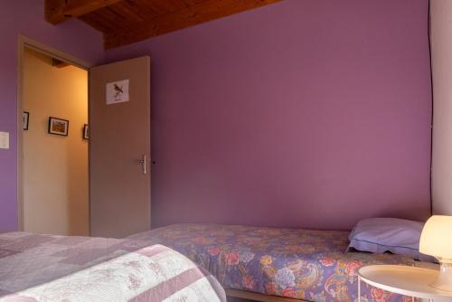 a bedroom with purple walls and a bed and a table at Gîte La Peyrade d'Aubrac 6/8 personnes in Marchastel