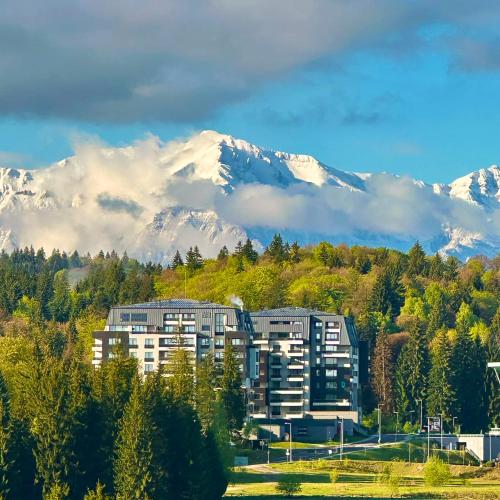 a building with snow capped mountains in the background at Joy Studio - Poiana Brasov - Silver Resort in Poiana Brasov
