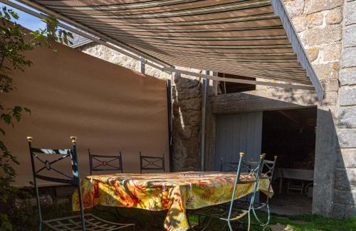 a patio with a table and chairs under awning at Gîte La Peyrade d'Aubrac 6/8 personnes in Marchastel