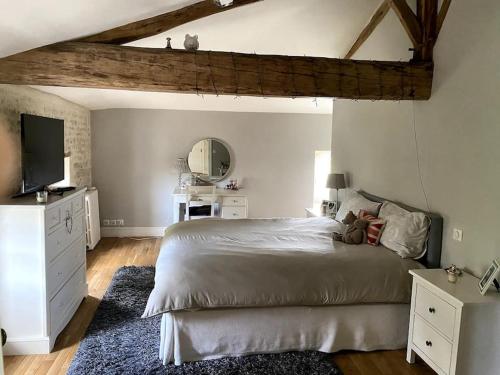 - une chambre avec un grand lit et une télévision dans l'établissement Le Mas, Maison de maître, Cognac, à Verrières