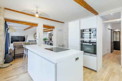 une cuisine avec des comptoirs blancs et un salon dans l'établissement Appartement des Verrières - Welkeys, à Avignon