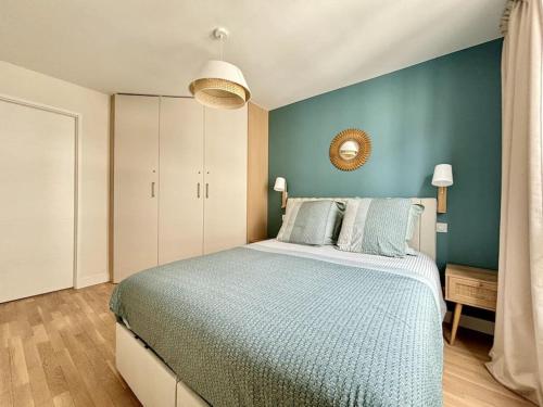 une chambre avec un grand lit avec un mur bleu dans l'établissement Appartement élégant hyper centre Arcachon plage classé 3 étoiles, à Arcachon