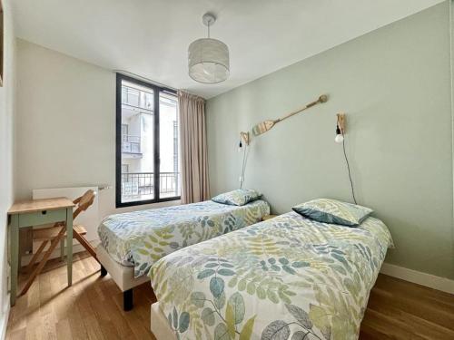 une chambre avec deux lits et un bureau et une fenêtre dans l'établissement Appartement élégant hyper centre Arcachon plage classé 3 étoiles, à Arcachon