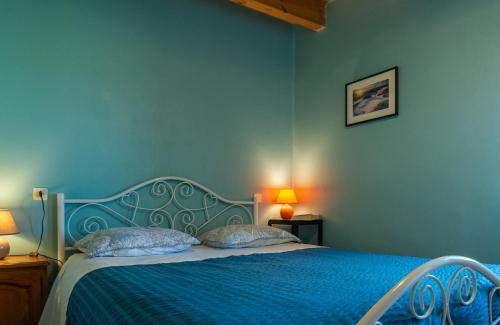 a blue bedroom with a blue bed with two pillows at Gîte La Peyrade d'Aubrac 6/8 personnes in Marchastel