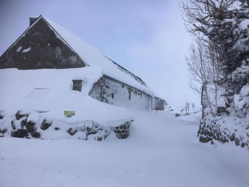 a barn covered in snow in a yard at Gîte La Peyrade d'Aubrac 6/8 personnes in Marchastel