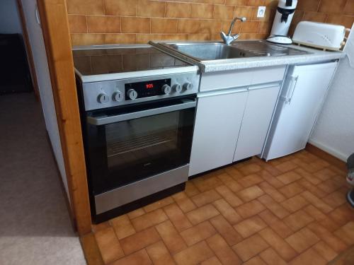 une cuisine avec une cuisinière et un évier dans l'établissement Studio cosy avec balcon, équipé pour 4, à 2 pas du centre et des remontées mécaniques de Super-Châtel - FR-1-676-130, à Châtel