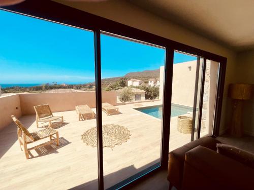 un salon avec vue sur un patio et l'océan dans l'établissement Villa Casa Damicella Bord de Mer avec Piscine, à Palasca