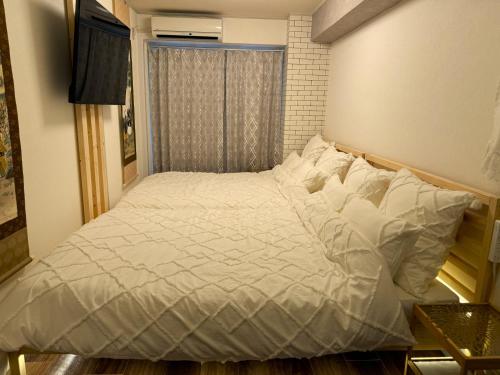 a bedroom with a bed with white sheets and a window at Elena Shinsaibashi Stay in Osaka