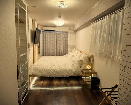 a small bedroom with a bed and a window at Elena Shinsaibashi Stay in Osaka