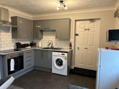 a kitchen with a washing machine and a washer at Walnut House - Modern 1 Bedroom Apartment very close to town by Shortstays4u in Kings Lynn