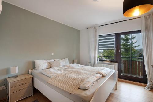 Un dormitorio con una cama y una ventana grande. en 2-Zimmer Ferienwohnung Am Waldrand, en Schönwald