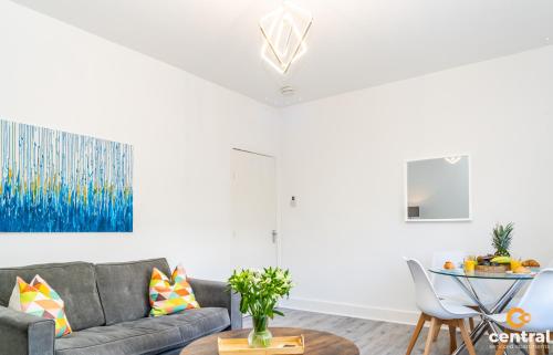 a living room with a couch and a table at Sandeman by CENTRAL SERVICED APARTMENTS - 2 Bedroom - FREE Street Parking - Fast WiFi - Smart TVs in All Rooms - Ground Level - Family Neighbourhood - 3 x Double Beds - Heating 24-7 - Trade Stays - Weekly & Monthly Offers in Dundee