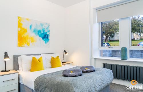 a bedroom with a bed with yellow pillows and a window at Sandeman by CENTRAL SERVICED APARTMENTS - 2 Bedroom - FREE Street Parking - Fast WiFi - Smart TVs in All Rooms - Ground Level - Family Neighbourhood - 3 x Double Beds - Heating 24-7 - Trade Stays - Weekly & Monthly Offers in Dundee