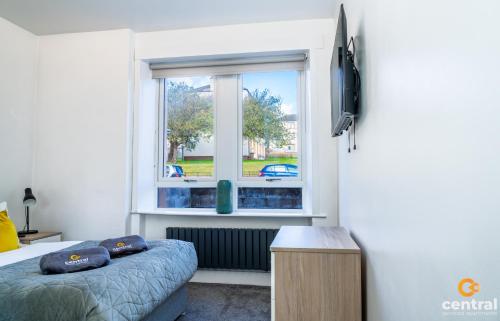 a bedroom with a bed and a window at Sandeman by CENTRAL SERVICED APARTMENTS - 2 Bedroom - FREE Street Parking - Fast WiFi - Smart TVs in All Rooms - Ground Level - Family Neighbourhood - 3 x Double Beds - Heating 24-7 - Trade Stays - Weekly & Monthly Offers in Dundee