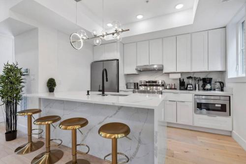 a kitchen with white cabinets and bar stools at Capitol Hill 4 Charming Townhouse in Downtown DC with Rooftop Free Parking and WIFI in Washington, D.C.