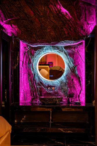 a room with a round mirror on a purple wall at Canyon Santorini in Fira