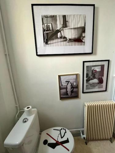 a bathroom with a white toilet and pictures on the wall at F2 parking Gare in Melun