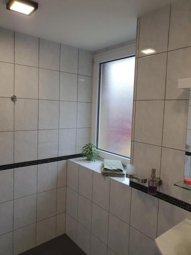 a white tiled bathroom with a window and a sink at Pension Valentina in Mühlau