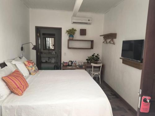 a bedroom with a white bed and a flat screen tv at Green 53 Boutique Hotel in Ilhéus