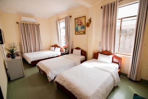two beds in a room with two windows at Minh Hiếu Hotel in Hue