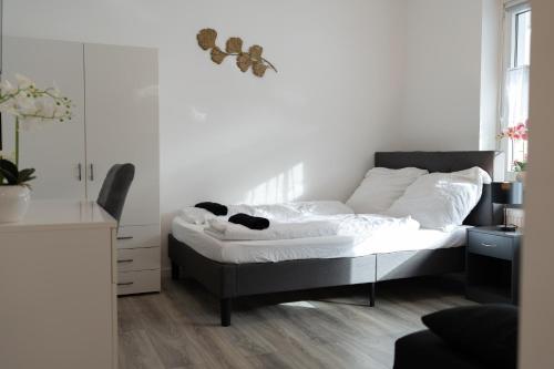 une chambre avec un lit avec des draps blancs et un bureau dans l'établissement Business Apartment 5 Essen, à Essen