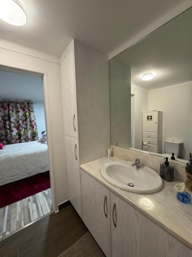 a bathroom with a sink and a bedroom with a bed at Sofiamarholidays O Cantinho da Avó Bina in Moita