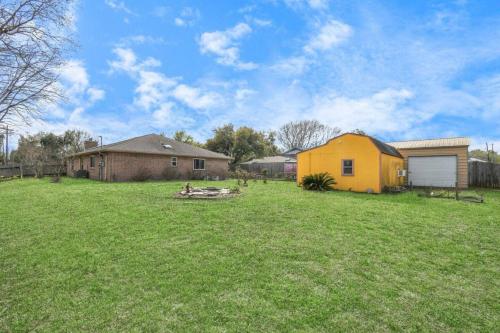 a yard with a yellow house in the middle at Peaceful Waters Your Intimate Hot Tub Escape in Houston