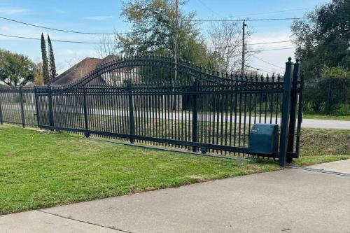 a black metal fence with a trash can in a yard at Peaceful Waters Your Intimate Hot Tub Escape in Houston