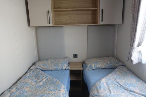two beds in a small room with a desk and cabinets at Red Lion Holiday Park in Arbroath