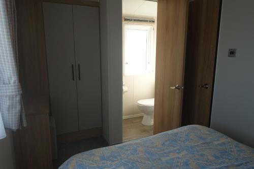 a bedroom with a bed and a bathroom with a toilet at Red Lion Holiday Park in Arbroath