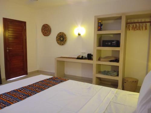 a bedroom with a bed and a clock on the wall at Aluna Beach House Nungwi in Nungwi