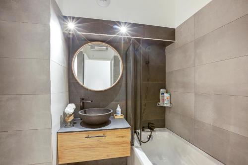 une salle de bain avec un lavabo, une baignoire et un miroir dans l'établissement Studio Cozy Juan les Pins Calme et Proximite, à Antibes