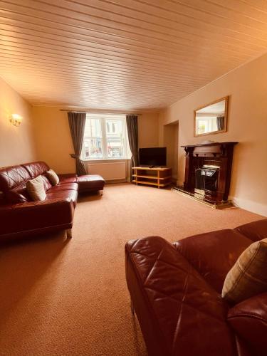 a living room with leather couches and a television at McKays Hotel in Pitlochry