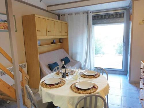 - une table à manger avec un chiffon de table blanc et des bouteilles de vin dans l'établissement Pavillon proche plage, à Narbonne