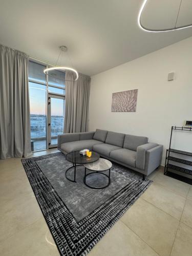 a living room with a couch and a table at Cozy 1BR Pool-Gym, close to metro BrandNew! in Dubai