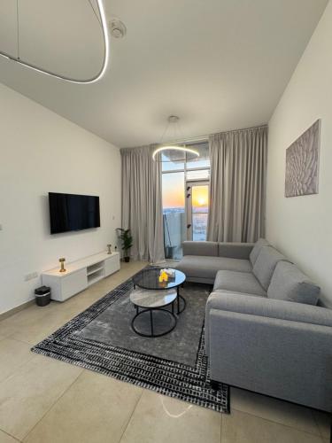 a living room with a couch and a tv at Cozy 1BR Pool-Gym, close to metro BrandNew! in Dubai