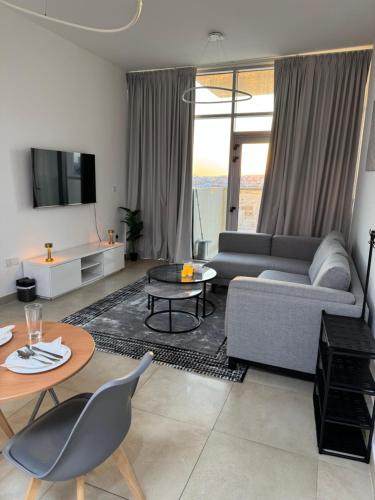 a living room with a couch and a table at Cozy 1BR Pool-Gym, close to metro BrandNew! in Dubai