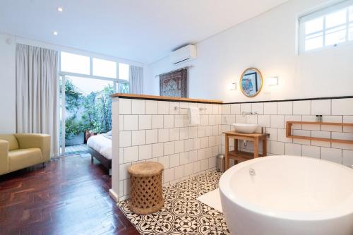 a white bathroom with a tub and a couch at Casa Velasur, De Waterkant in Cape Town